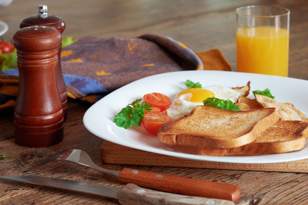 Breakfast with scrambled eggs, bacon, toast and fresh vegetables.の写真素材