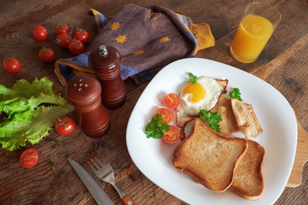 Breakfast with scrambled eggs, bacon, toast and fresh vegetables.の写真素材