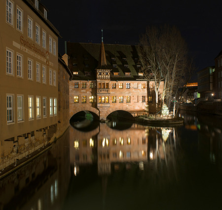 Monastery Holy Spirit Hospice on the river bank and bridge at night in Nuremberg, Germany.のeditorial素材
