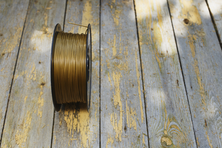 Gold filament for 3D Printer on old wooden table, selective focusの写真素材