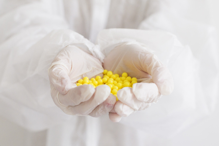 Close-up shot of a vitamins in hands. White gloves with medicine pillsの写真素材