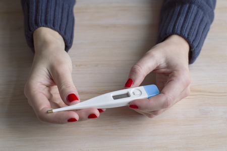 Womens hands with a thermometer
