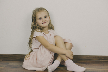 Girl smiles wistfully, sitting on the floorの写真素材