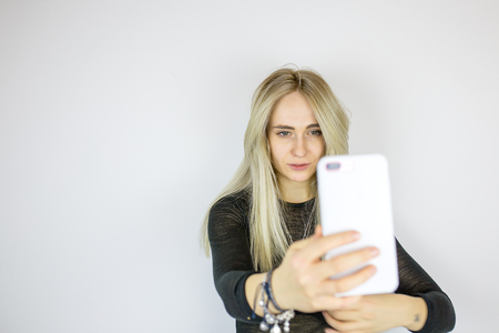 Modern blonde takes a selfie on the phoneの写真素材