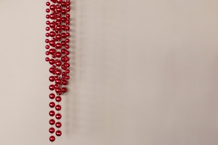 A wall of light brown color on which red shiny beads hang beautifullyの写真素材