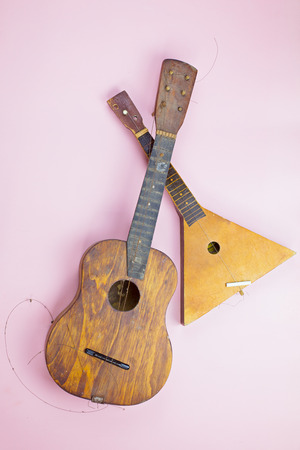 Old wooden musical instruments: guitar and balalaika on a pink backgroundの写真素材