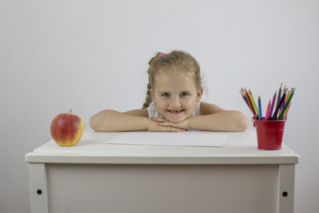 Girl schoolboy at her desk with pencils looks and smilesの写真素材
