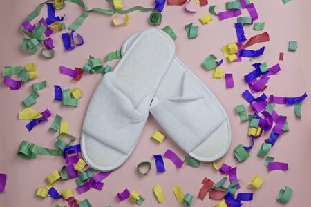 White disposable bath slippers on the background of multicolored confettiの写真素材