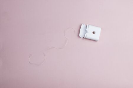 Open dental floss in a white plastic box on a pink background. Top viewの写真素材