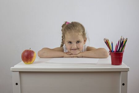 Schoolgirl at her desk with a cheerful facial expressionの写真素材