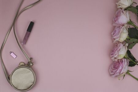 Womens handbag near which is lipstick and flash card. Large roses on a pink backgroundの写真素材