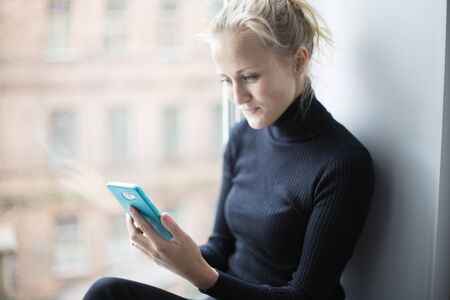 Attractive girl looks at the phone and smiles