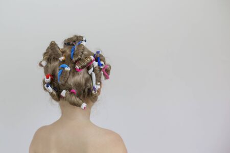 The child stands with his back, and multi-colored curlers on his hairの写真素材