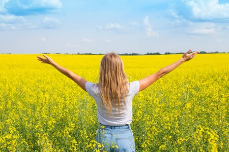 The girl spread her arms while standing with her back in the field. Wish fulfillment conceptの写真素材