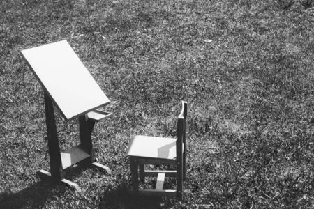 Wooden easel and a chair on the grass. Black and white photo