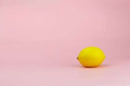 Ripe lemon on a gently pink background with place for textの写真素材