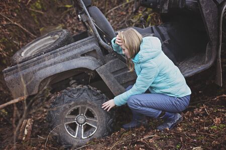 Woman shocked by an estremal ride on UTV. Checks the status of a buggy that has rolled down a mountain into a ditch. Extreme ATV Ridingの写真素材