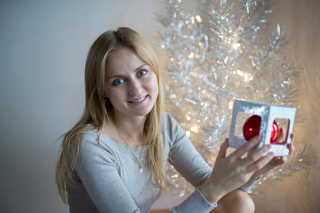 Beautiful girl decorates a Christmas tree.Holiday and good moodの写真素材