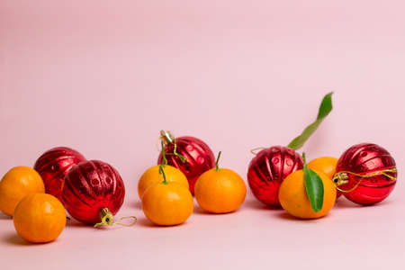 Orange tangerines and red balls lie against a pink background. Festive background.の写真素材