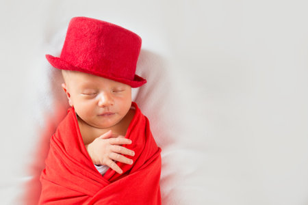 Portrait of newborn gentleman in the cylinder. Sleeping newborn baby in a red suit and hatの写真素材
