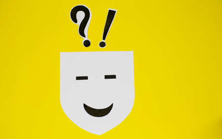Paper face expressing happiness with question and exclamation mark on top on yellow background