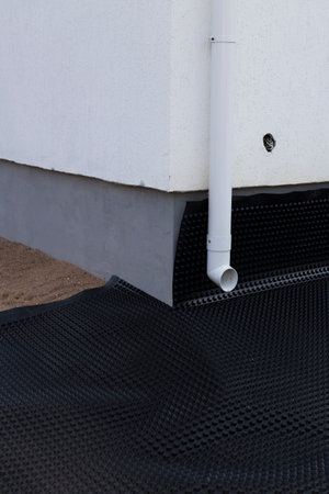 Black waterproofing membrane around the foundation of the house. Construction of the blind area of the house. Reliable protection of the foundation from moisture.の写真素材