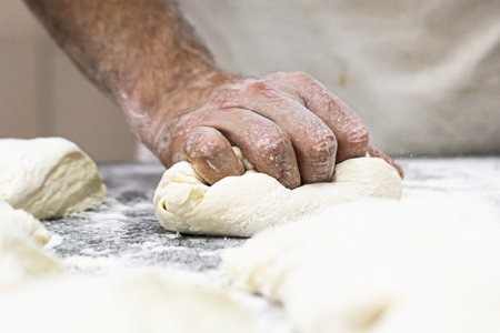 Worker of a pizza factory kneading with a lot of energy to make a perfect bun