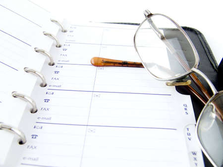 The opened notebook and glasses on a white backgroundの写真素材