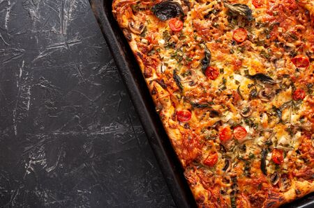 Fresh delicious hot pizza with mushrooms, cherry tomatoes, Basil and Parmesan on a rectangular pan...