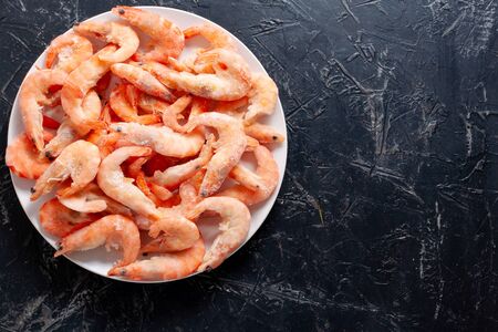 Frozen king prawns on a white plate on a dark backgroundの写真素材