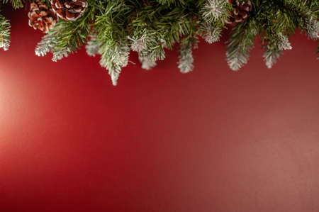 Christmas garland with green fir branches and cones on the background of a red wall with space for text. Copy space. Shallow depth of field and selective focus.の写真素材