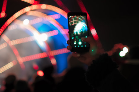 Blurry bokeh Light on a dark background. Defocused Image of an Illuminated outdoor stage area at Night. Unfocused stage lights and crowds with smartphones in their hands at a concertの写真素材