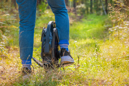 Rear view of women's legs on an electric unicycle in the forest on a sunny day