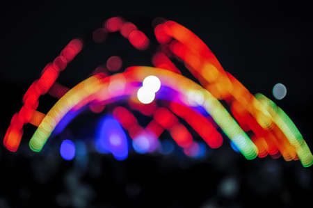 Blurred bokeh Light on a dark background. Defocused Image of an Illuminated outdoor stage area at Night. Unfocused stage lights and the crowd at the concertの写真素材