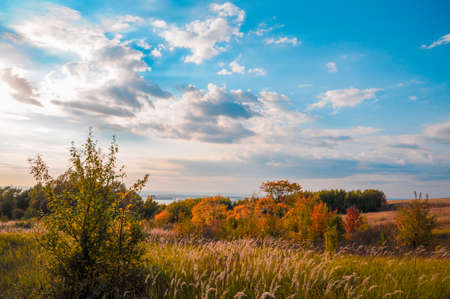 A colorful autumn landscape on a cloudy day, a view of the sunlit hills, the river below and the...