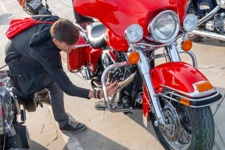 Kazan, Russia-September 26, 2020: A man on his phone takes pictures of the details of a red Harley...