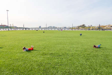 Kazan, Russia-September 26, 2020: Children play and roll on the artificial lawn of the artificial football field in the city park on the embankment on a weekendのeditorial素材