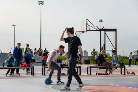 Kazan, Russia-September 26, 2020: In the city park on the embankment, young people play basketball, residents walk, children and teenagers race on scooters, skateboards and bicycles on the ride area.のeditorial素材