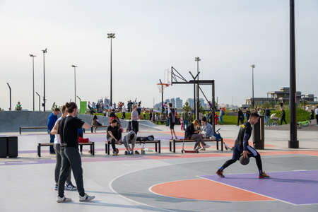 Kazan, Russia-September 26, 2020: In the city park on the embankment, young people play basketball, residents walk, children and teenagers race on scooters, skateboards and bicycles on the ride area.のeditorial素材