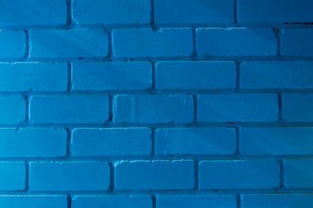 An old brick wall, painted blue, lit by the slanting rays of the sun.の写真素材