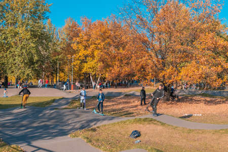 Kazan, Russia - October 03, 2020: Children and teenagers ride scooters and bicycles in the city's public park on a sunny autumn dayのeditorial素材