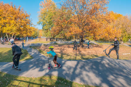 Kazan, Russia - October 03, 2020: Children and teenagers ride scooters and bicycles in the city's public park on an autumn sunny dayのeditorial素材