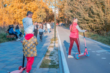 Kazan, Russia - October 03, 2020: Children and teenagers on scooters ride along the bike path in the...