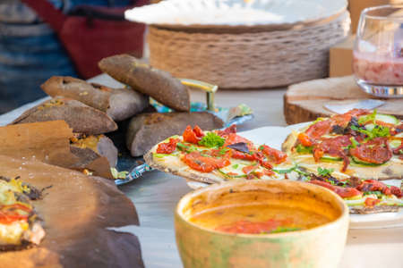 Round pizza made of black dough. Barbecue festival in the city park. Street fast food.