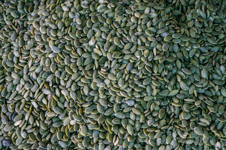A pile of peeled pumpkin seeds, a stand with pumpkin seeds in close-up at the farmer's market. Copy space.の写真素材