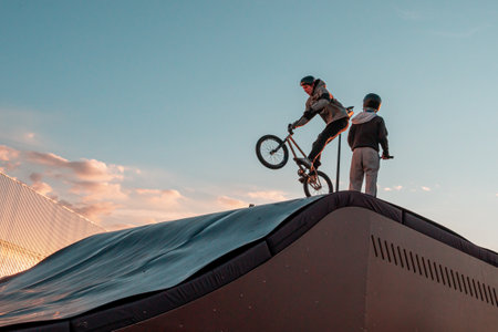 Young riders on BMX bicycles on the ramp of the skate park in the city public park for active recreationのeditorial素材