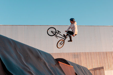 A BMX rider does a stunt on a ramp in a skate park in the city public park for outdoor activities
