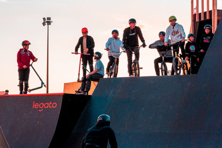 A group of young riders on BMX bicycles on the ramp of a skate park in the city public park for active recreationのeditorial素材