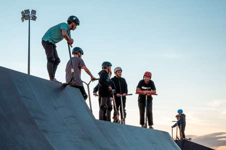 A group of young riders on BMX bicycles on the ramp of a skate park in the city public park for active recreationのeditorial素材
