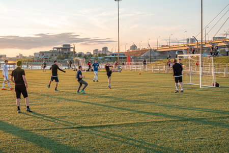 Young football players play football on the field in the city public park on a summer evening.のeditorial素材